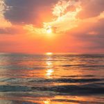 sea under white clouds at golden hour