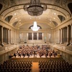 music group performing on stage with empty audience seats