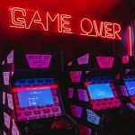 a neon sign that says game over in front of a row of arcade machines