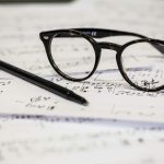 black framed panto-style eyeglasses beside black ballpoint pen